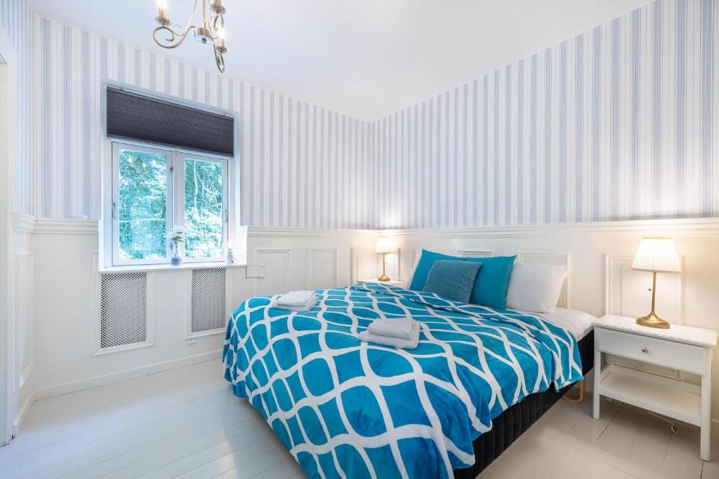 a bedroom with a blue and white bed and a window at Velling Koller Hotel og Camping in Bryrup