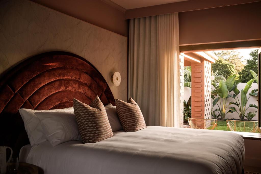 Swell Hotel Byron Bay - Adults Only في خليج بايرون: غرفة نوم بسرير كبير مع نافذة كبيرة