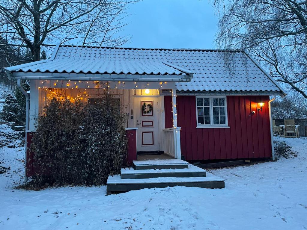a small red house with lights in the snow at Koselig anneks i Heggedal! in Asker