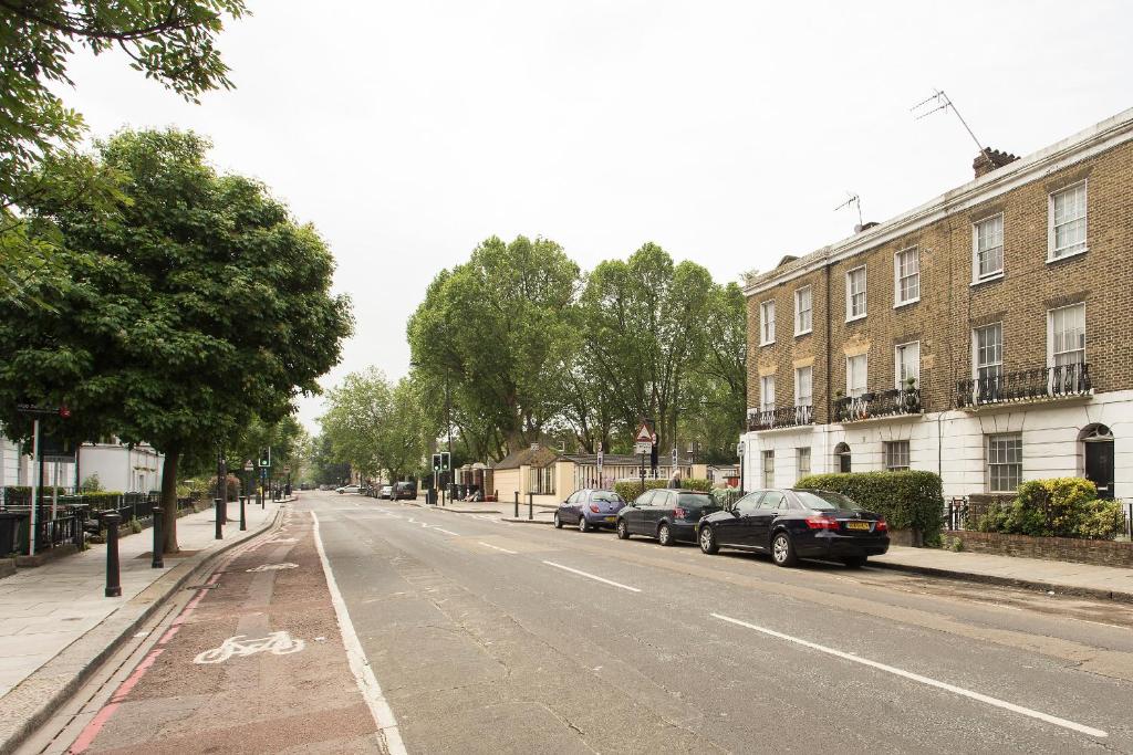 an empty street with parked cars and buildings at Camden Apartment By Morethanstays in London