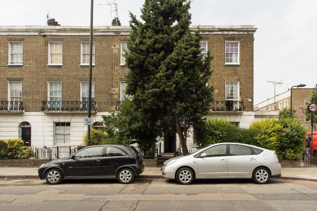 two cars parked in a parking lot in front of a building at Camden Apartment By Morethanstays in London
