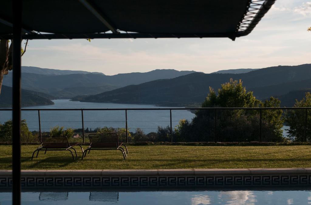 two benches sitting in front of a view of a lake at Casa Boumort in Sant Marti de Canals