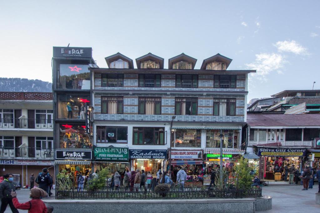 un gran edificio con una multitud de personas delante de él en Hotel Vijayant en Manāli