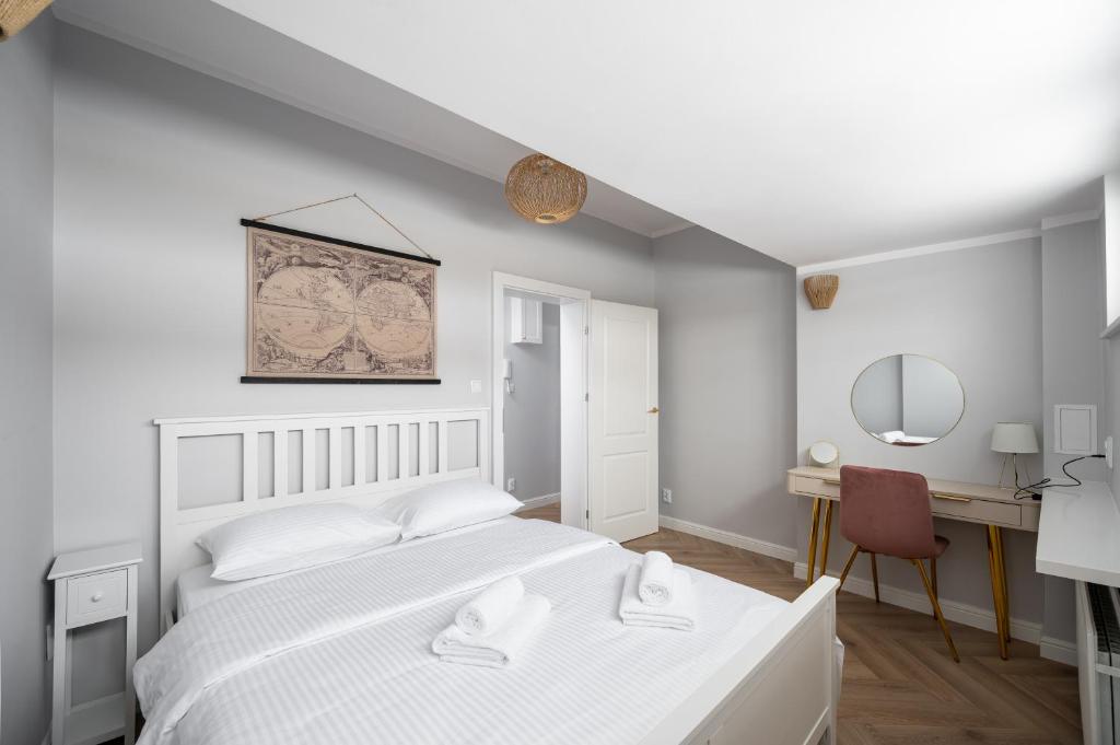 a bedroom with a white bed and a desk at Nowy Świat 22 Luxury Apartment in Warsaw