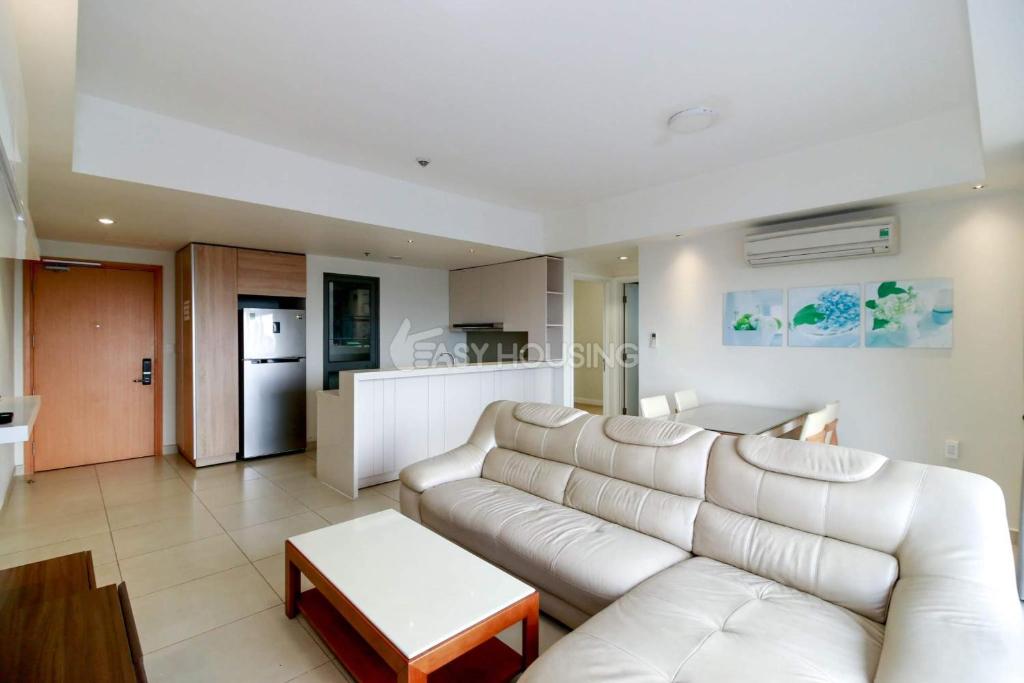 a living room with a white couch and a kitchen at Masteri Thao Dien by Aura Luxury in Ho Chi Minh City