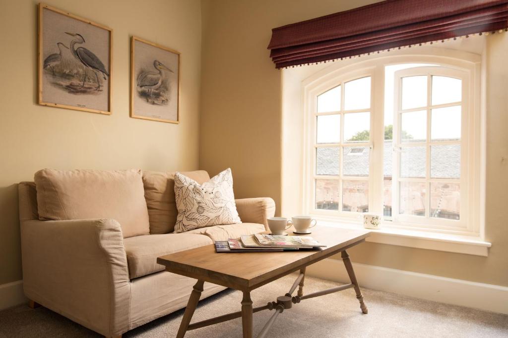 ein Wohnzimmer mit einer Couch und einem Tisch und einem Fenster in der Unterkunft Birch Cottage in Cockburnspath