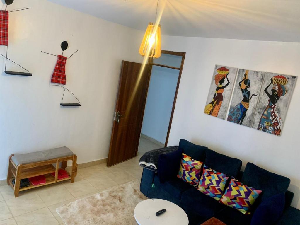 a living room with a blue couch and paintings on the wall at Rorot 1 bedroom Kapsoya with free wifi and great views! in Eldoret