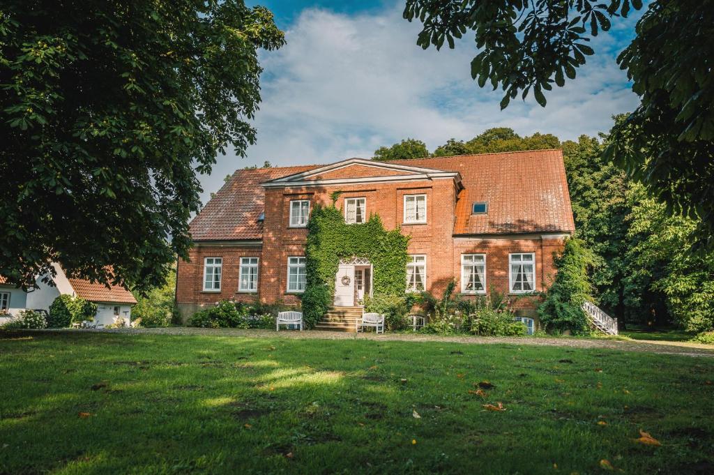 a large brick house with a green yard at Gutshaus Krimvitz Kleines Doppelzimmer inkl Frühstück in Putbus