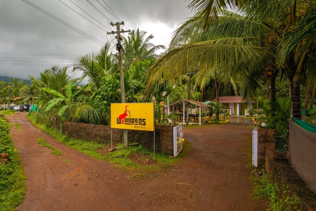 um sinal amarelo no lado de uma estrada de terra batida em Whoopers Home Palolem em Marmagao