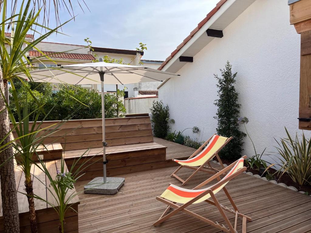 2 chaises et un parasol sur une terrasse en bois dans l'établissement Ocean Lodge_plage Bourdaines, à Seignosse