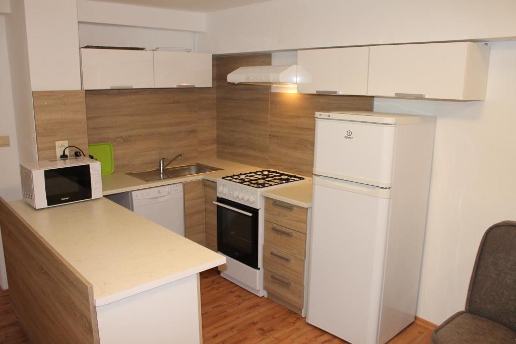 a small kitchen with white appliances and wooden walls at Suterénový apartmán v centre in Piešťany