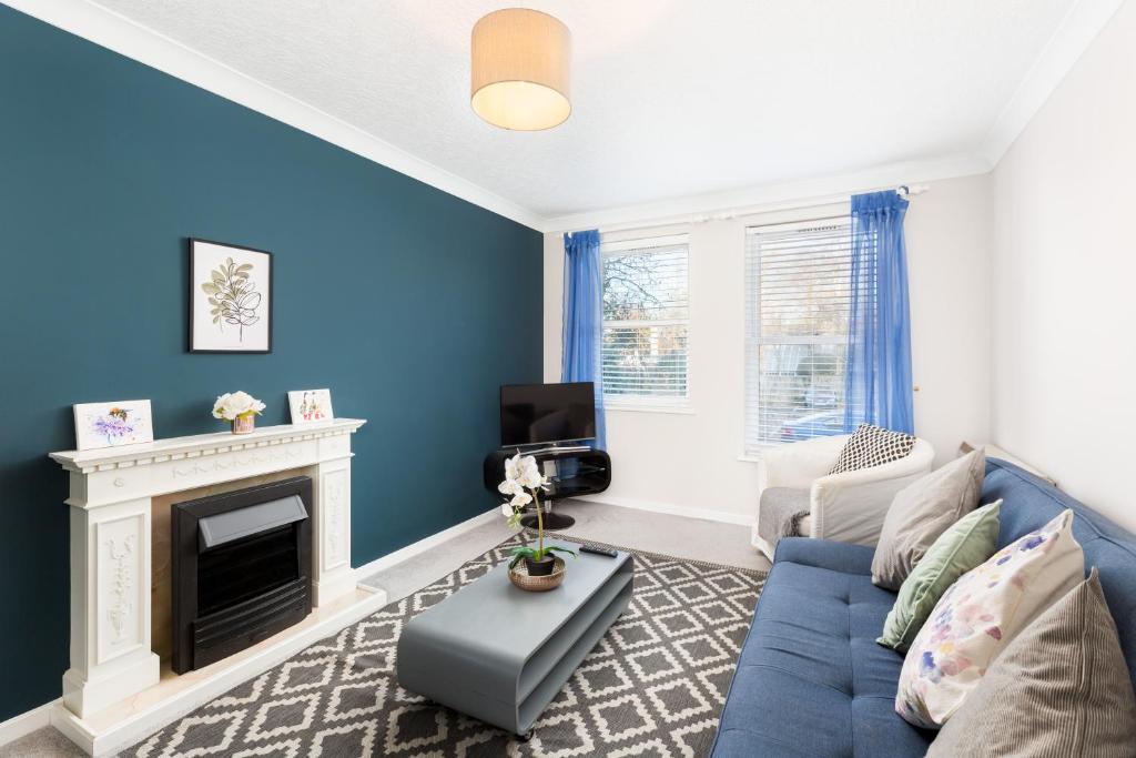 Sala de estar azul con sofá y chimenea en NEWLY RENOVATED, Chestnut Court, 2-Bedroom Apts, Private Parking, Fast Wi-Fi, en Leamington Spa
