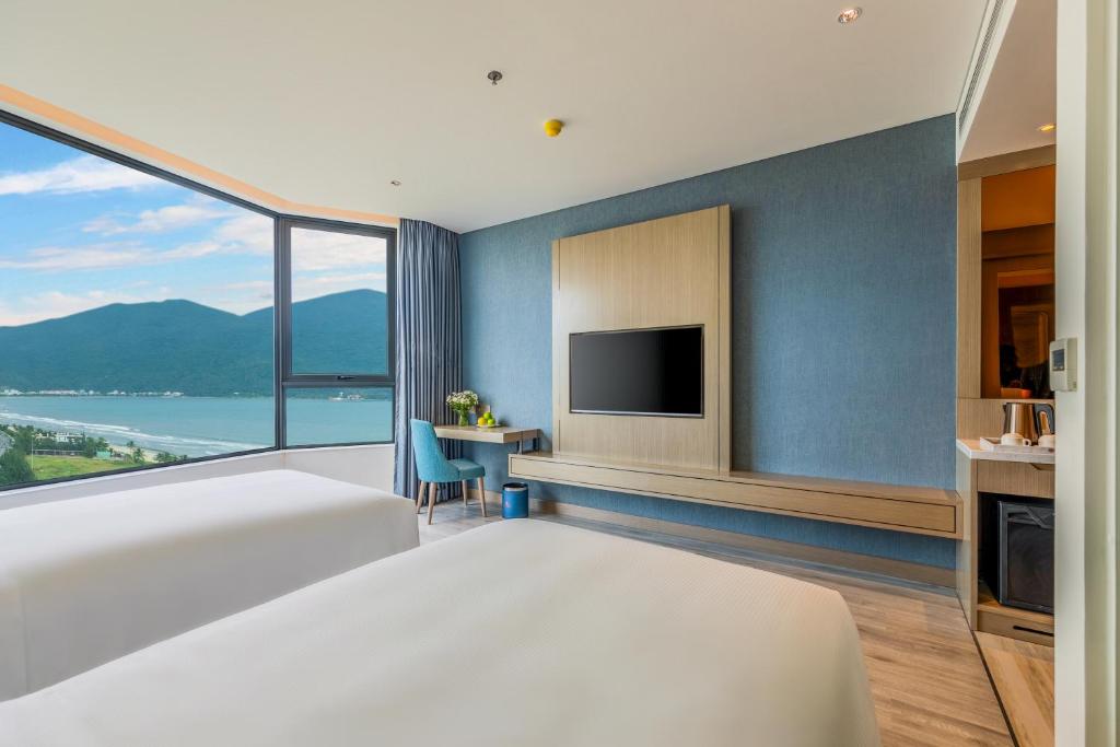 a bedroom with a large bed and a tv at Awaken Da Nang Hotel in Danang