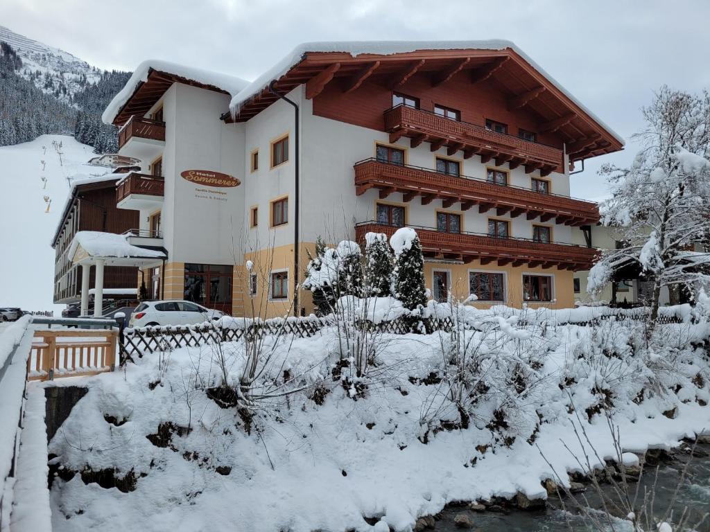 een groot gebouw met sneeuw op de grond bij Hotel Sommerer in Saalbach Hinterglemm
