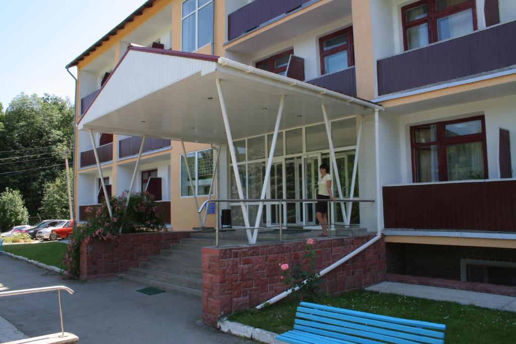 a woman standing outside of a building with a white awning at Санаторій Збруч in Satanov