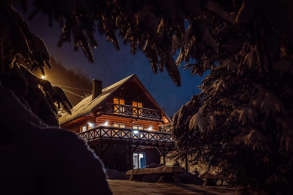 una cabaña de madera en la nieve por la noche en SZUMiPOTOK Szczyrk, en Szczyrk