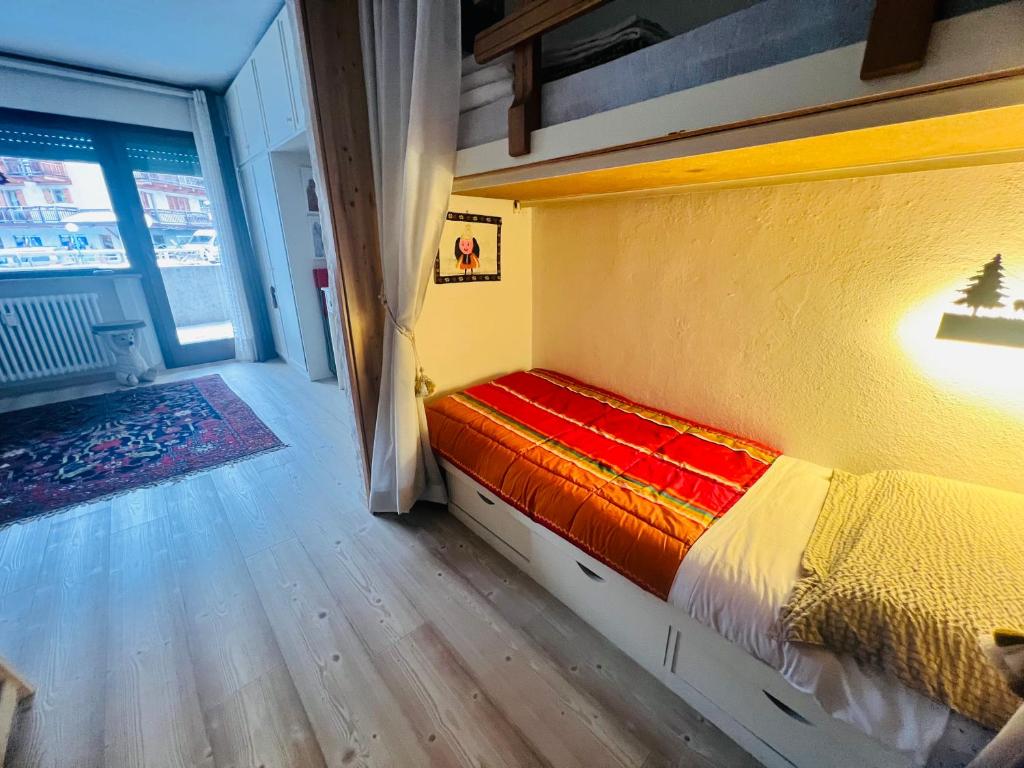 um quarto com uma cama com um cobertor vermelho e amarelo em Casa degli orsi - Madonna di Campiglio - Condominio Nardis em Madonna di Campiglio