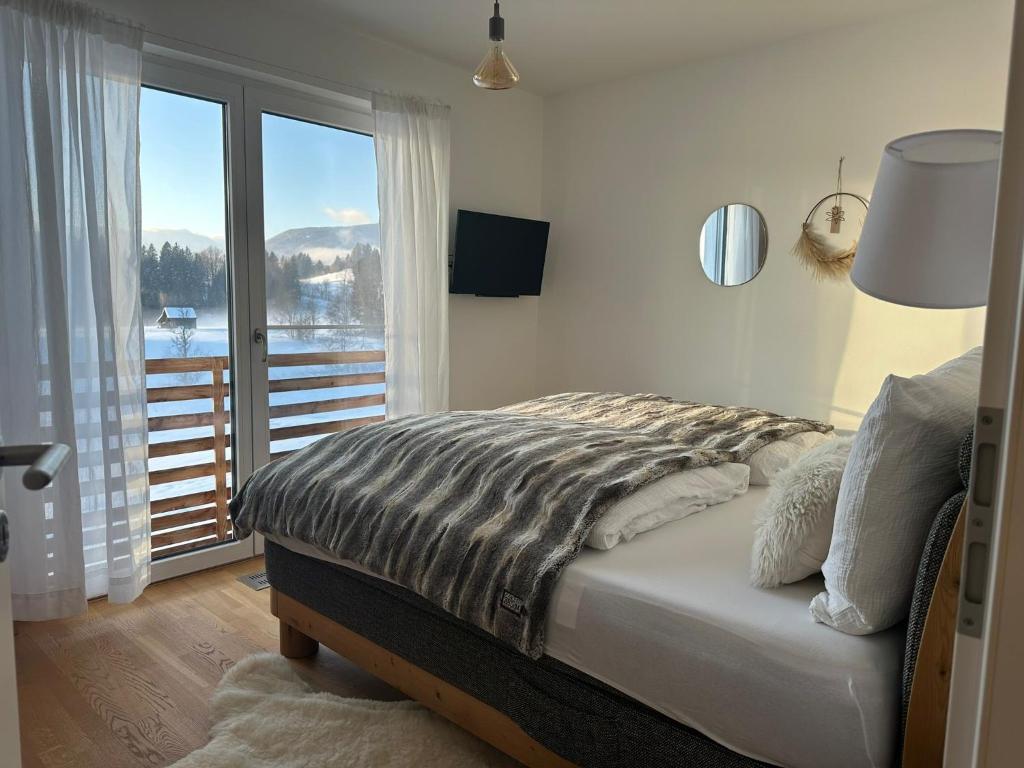 um quarto com uma cama e uma grande janela em ALPEN WOHLFÜHLQUARTIER em Bayersoien