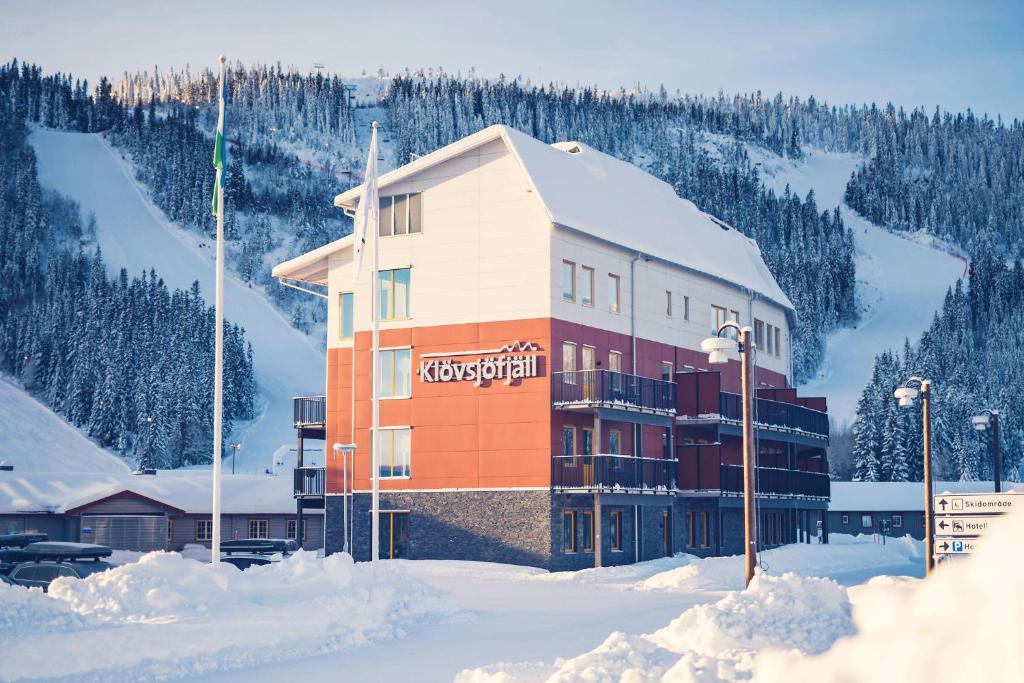 budynek w śniegu z górą w obiekcie Hotell Klövsjöfjäll w mieście Klövsjö