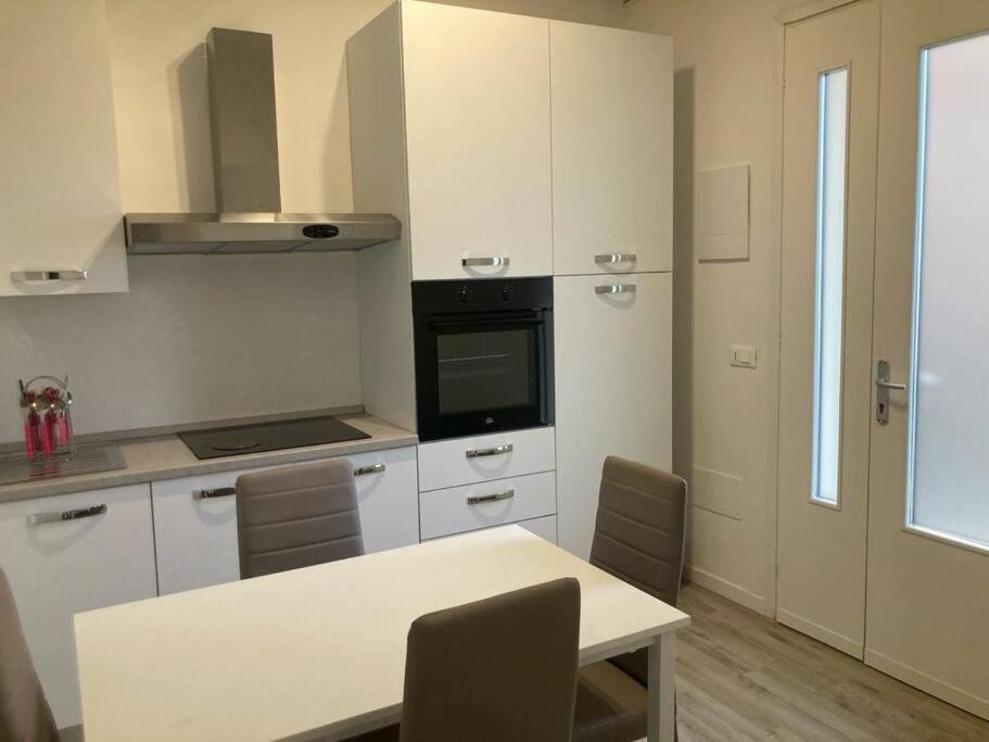 uma cozinha com armários brancos e uma mesa com cadeiras em Appartamento a 200 mt dal mare em Lido di Jesolo