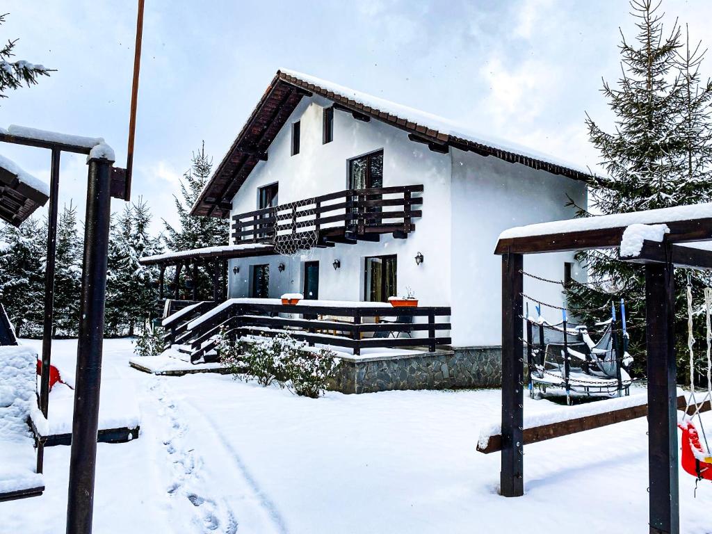 a white house with snow in front of it at Vila Alunis 2 in Bran