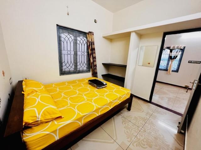 ein Schlafzimmer mit einem gelben Bett in einem Zimmer in der Unterkunft Lumina Home Stay in Puducherry