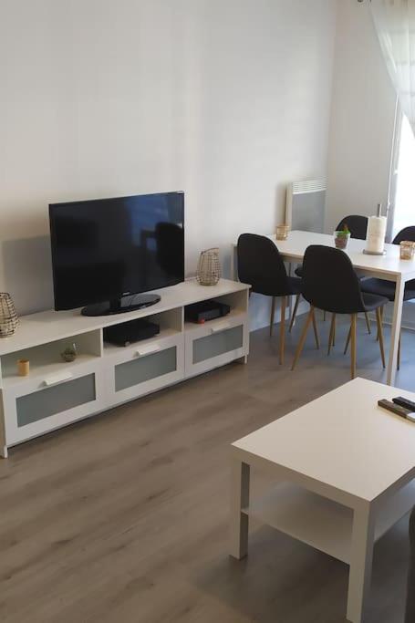 - un salon avec une télévision sur un centre de divertissement blanc dans l'établissement T2 de 42m² A proximité de la gare à 30min de PARIS, à Mantes-la-Jolie