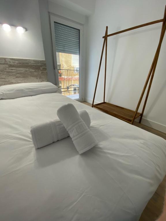Una cama blanca con dos toallas encima. en Apartamento Granada centro en Granada