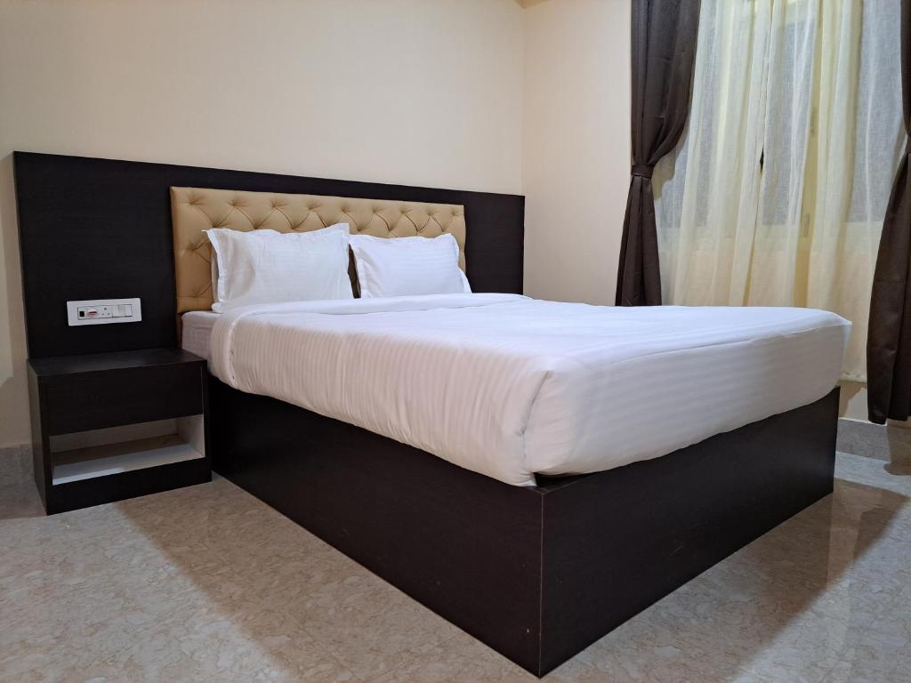 um quarto com uma cama grande com lençóis brancos e almofadas em snow white retreat hotel and restaurant em Gangtok