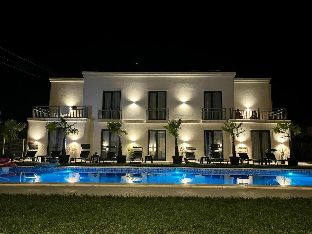 una grande casa bianca con piscina di notte di Villa Gyos a Costinesti