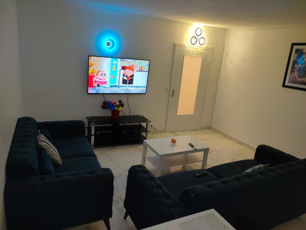sala de estar con 2 sofás y TV de pantalla plana en Mon superbe appartement en Argenteuil