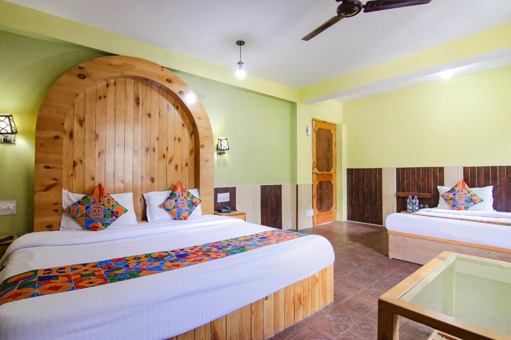two beds in a room with green walls at FabHotel River Bank in Vashisht