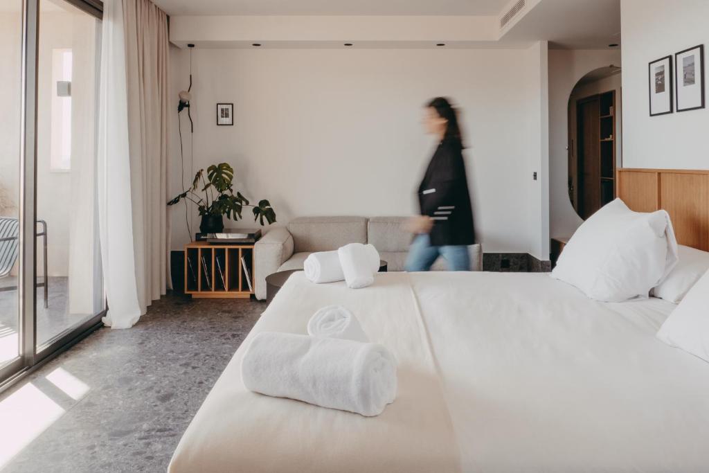 - une chambre blanche avec un grand lit et des serviettes dans l'établissement Hotel Moderne, à Porto-Vecchio