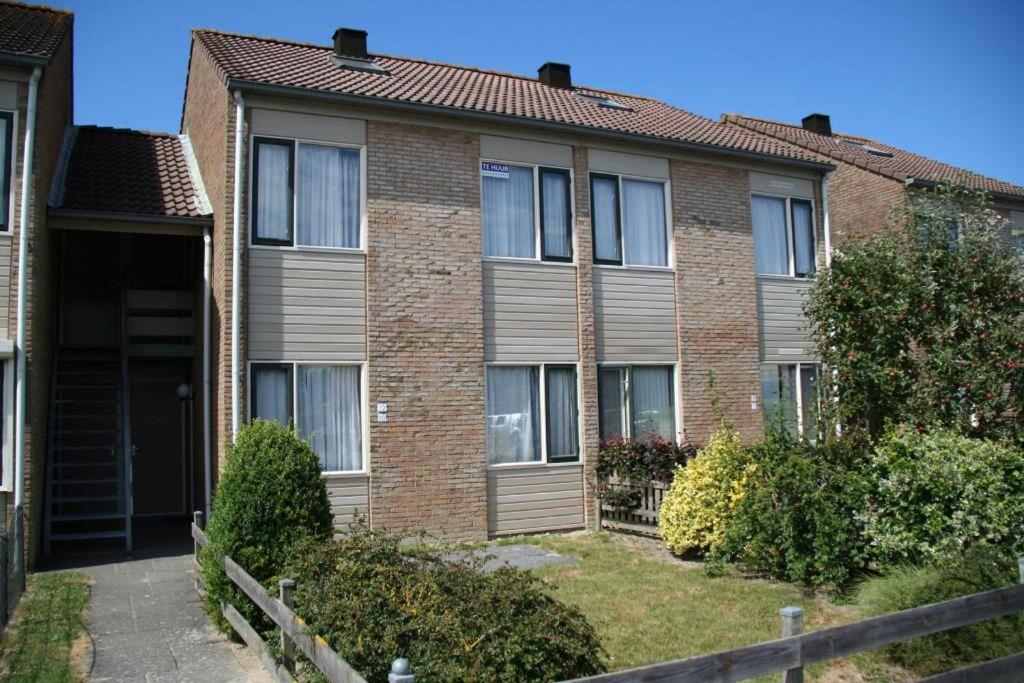 a brown brick building with a fence in front of it at Schorrebloem 9* in Nieuwvliet