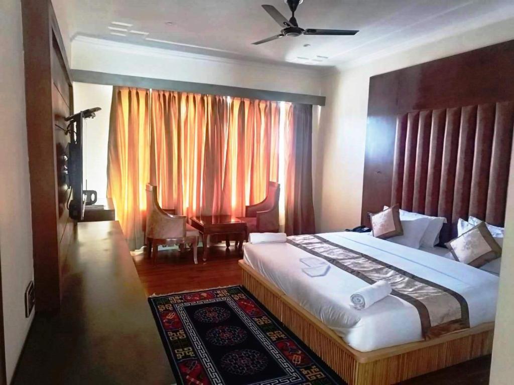 a bedroom with a large bed and a window with curtains at Hotel Ladakh Heaven in Leh