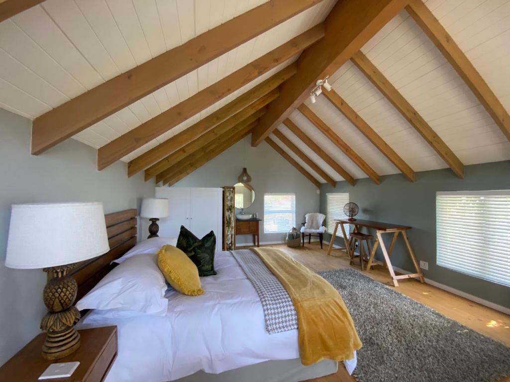 Un dormitorio con una cama con sábanas blancas y techos de madera. en The Vine en Bellville
