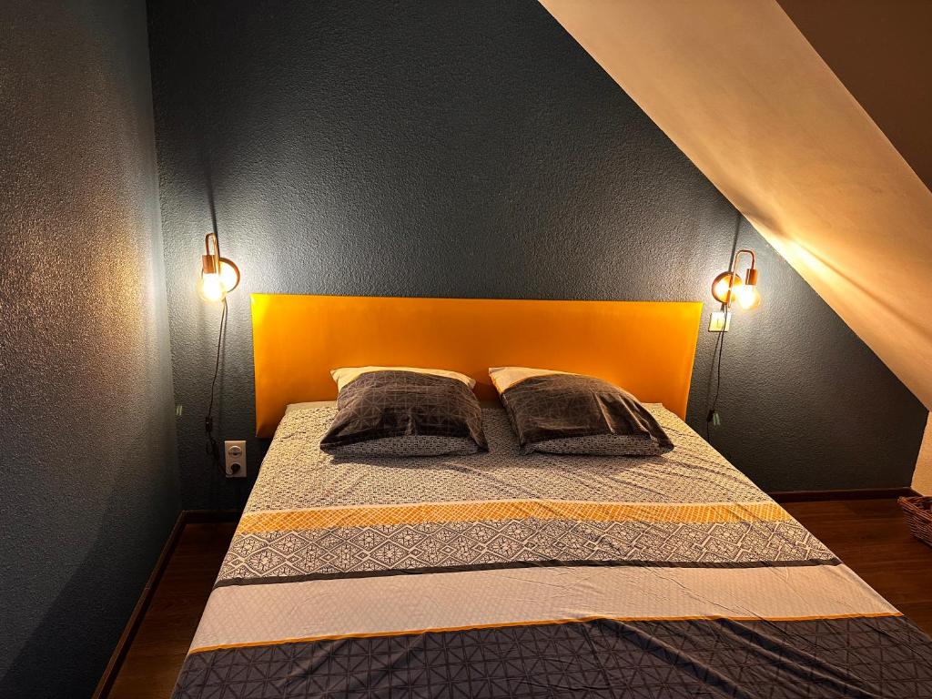 ein Schlafzimmer mit einem Bett mit orangefarbenem Kopfteil und zwei Kissen in der Unterkunft La Maison aux Volets Bleus 3ème Étage in Vic-sur-Cère