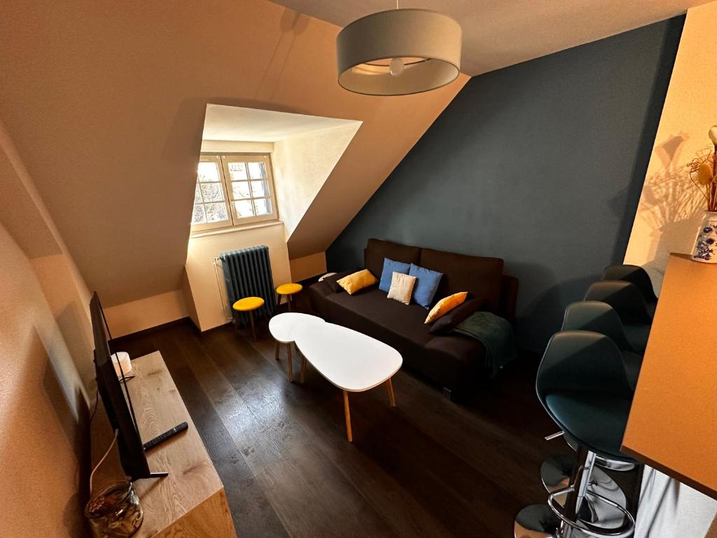 ein Wohnzimmer mit Sofa und Tisch in der Unterkunft La Maison aux Volets Bleus 3ème Étage in Vic-sur-Cère