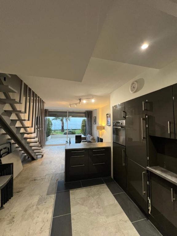 a kitchen with black cabinets and a staircase at Château de la mer, by Welcome to Cannes in Cannes