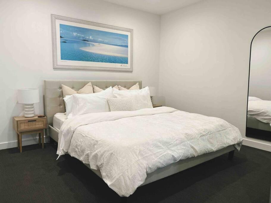 um quarto com uma cama branca e uma fotografia na parede em Glenelg Oasis, Pool, Gym, Spa & Sauna, Free Parking, City Views em Glenelg
