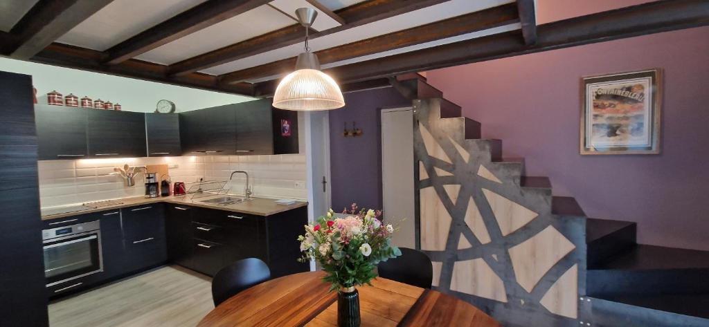 una cocina con una mesa con un jarrón de flores. en Bleautiful "Blanche" Charmant duplex tout confort, en Fontainebleau