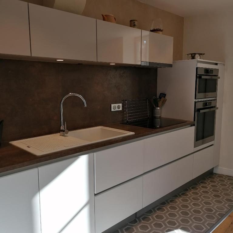 a kitchen with white cabinets and a sink at L Appart des Cloutiers in La Rochelle