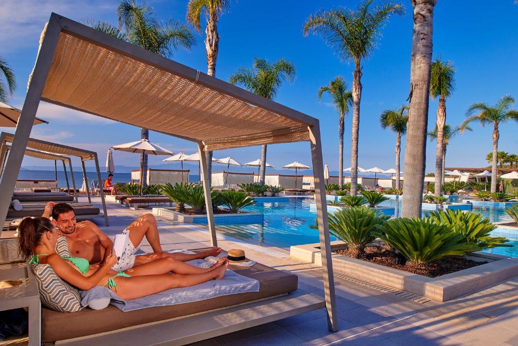 - un groupe de personnes dormant sur un lit à côté d'une piscine dans l'établissement Miraggio Thermal Spa Resort, à Paliouri