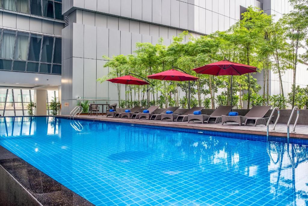 uma piscina com cadeiras e guarda-sóis em Ascott Sentral Kuala Lumpur em Kuala Lumpur