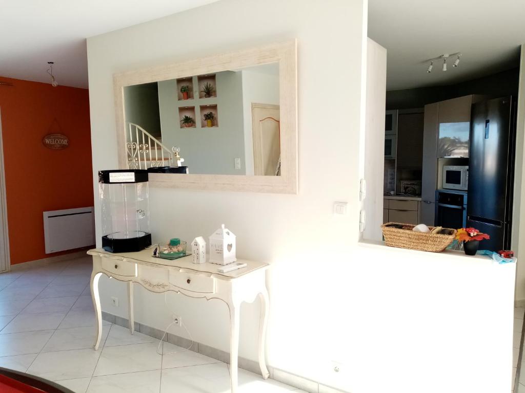 a kitchen with a white table and a mirror at 2 Chambres avec piscine et spa au calme, mer à proximité. in Portiragnes