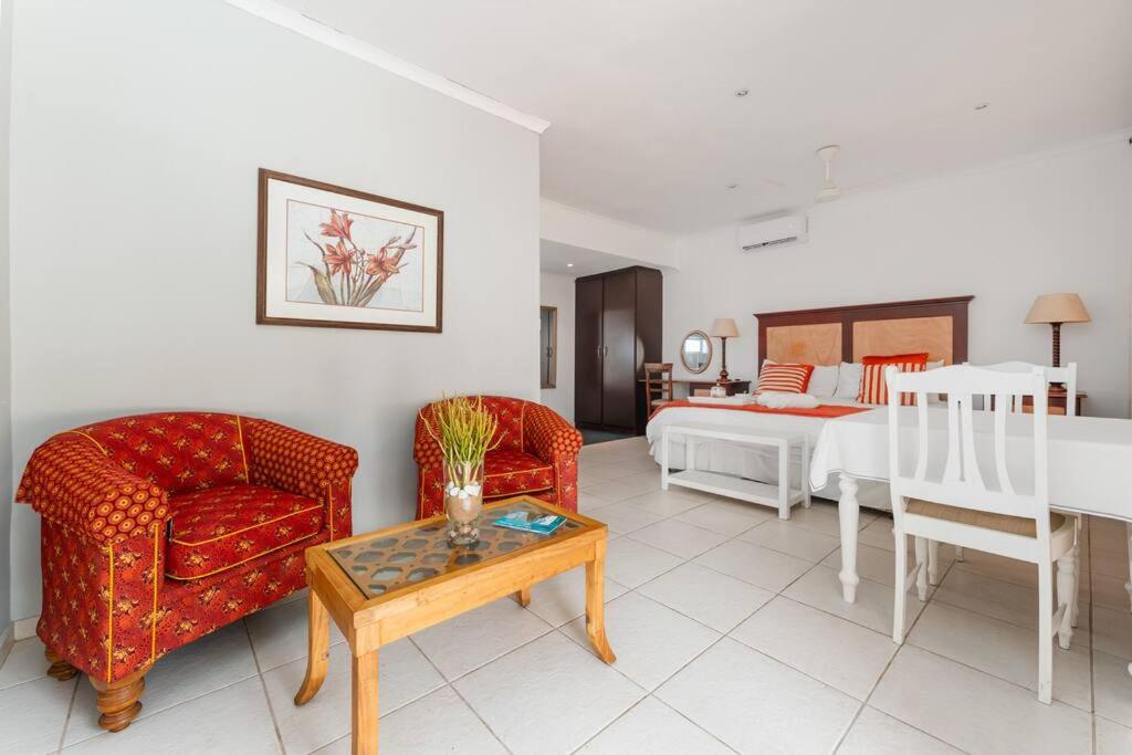 uma sala de estar com uma cama, um sofá e uma mesa em Lalaria Ocean Villa Suite 6 em Ballito