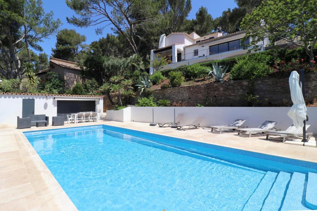 une piscine avec des chaises et une maison dans l'établissement Mesomax - Villa vue mer, piscine, proche de la mer - Appartement RDC, à Carqueiranne