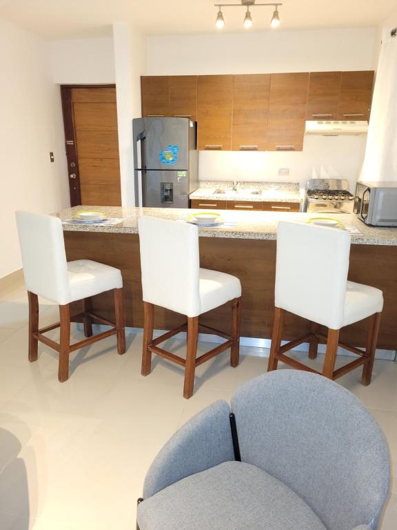 a kitchen with a counter with three chairs and a kitchen island at Serena 4 in Punta Cana
