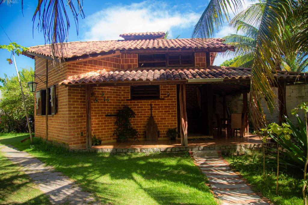 una casa de ladrillo con una palmera delante de ella en Casa por temporada a 250mts da praia, en Santa Cruz Cabrália