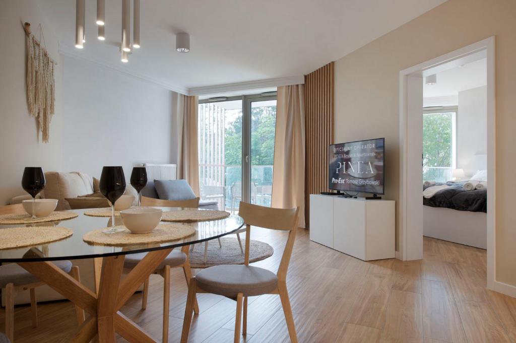 a living room with a dining table and a bedroom at Apartament Premium PINEA 107 in Pobierowo